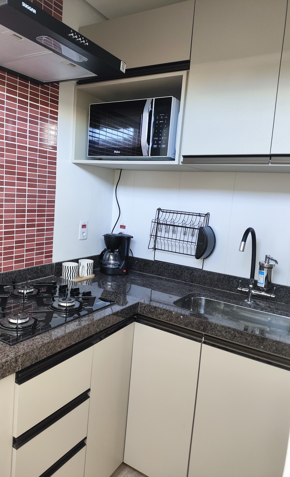 Cozinha equipada com cafeteira, cooktop e micro-ondas